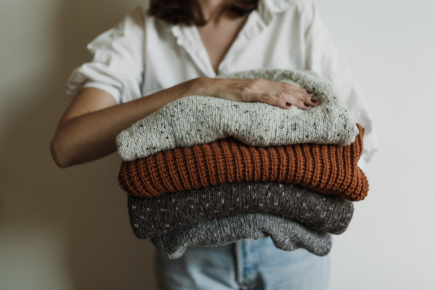 woman holding knitted jumpers